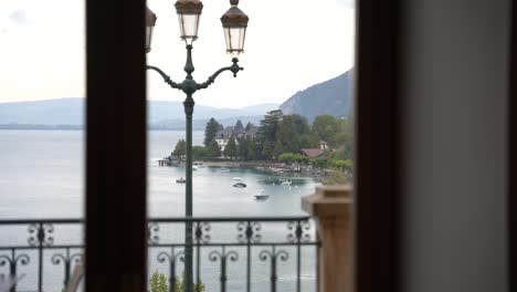 Lake-Annecy-seen-from-a-window-on-an-overcast-day-in-the-French-Alps-with-lamppost,-Medium-shot