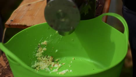 Older-Man-Grinding-Apples-with-an-Electric-Grater-into-a-Green-Bucket