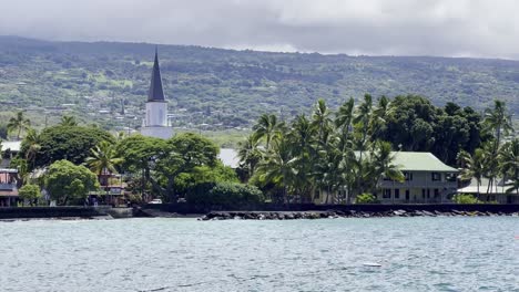 Cinematic-booming-up-shot-of-Moku‘aikaua-Church-and-Hulihe'e-Palace-across-Kailua-Bay-in-historic-Kona-Town-on-the-Big-Island-of-Hawai'i