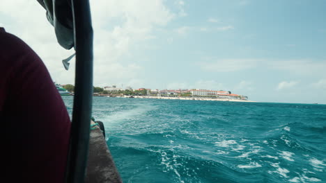 Boat-view-of-Stone-Town's-coastline-and-choppy-turquoise-waters