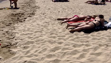 Two-girls-enjoy-a-fantastic-sunny-day-at-Guincho-Beach-in-Cascais,-chatting-and-having-a-great-time