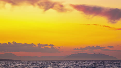 In-Malaga,-Spanien,-Zeigt-Der-Fesselnde-Zeitraffer-Eine-Atemberaubende-Meereslandschaft-Mit-Majestätischen-Bergen,-Wolken-Und-Der-Reflexion-Strahlender-Gelbtöne-Des-Sonnenlichts