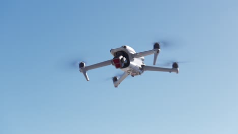 Moderne-Weiße-Drohne-Schwebt-Mit-Blauem,-Klarem-Himmel-Für-Kopierraum-Im-Hintergrund