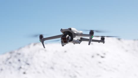 Weiße-Drohne-Schwebt-Mit-Schneebedeckten-Bergen-Im-Hintergrund