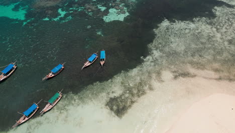 Tropical-beach-with-traditional-boats-and-visitors-from-an-aerial-view