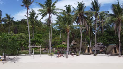 People-relaxing-on-Palm-tree-hammock-at-tropical-resort-huts-of-Coco-Beach-on-Bulalacao-island