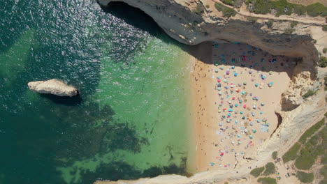 Aerial-view-of-crowded-Praia-do-Carvalho-in-Algarve,-Portugal-with-umbrellas-on-the-sand-during-a-sunny-summer-day