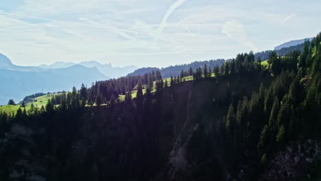 Sideways-aerial-pan-along-mountain-ridgeline-with-panoramic-vista-over-mountain-backdrop