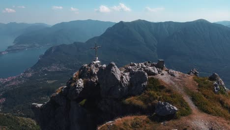 fast-moving-drone-video-of-a-man-sitting-by-the-cross-on-top-of-monte-grona-near-lake-como-in-italy