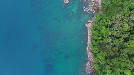 Tropisches-Paradies:-Ein-Atemberaubender-Vertikaler-Drohnenflug-über-Die-Steinküste,-Die-Grünen-Wälder-Und-Das-Blaue-Wasser-Der-Insel-Phuket-In-4K