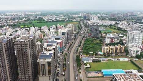 The-aerial-drone-camera-is-moving-over-the-ring-road-in-the-middle-of-Rajkot-city-with-lots-of-vehicles-on-the-road-and-high-rise-buildings-on-both-sides