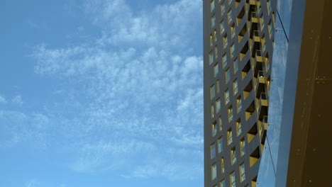 High-rise-building-with-golden-hued-windows-against-a-blue-sky