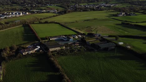 Aerial-view-looking-down-over-small-Anglesey-village-farming-business-surrounded-by-vibrant-agricultural-farmland