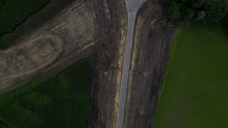 Road-construction-process-through-agriculture-fields,-aerial-top-down-view