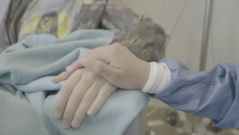 A-person-in-the-hospital-receiving-hand-touches-and-support-from-family-members