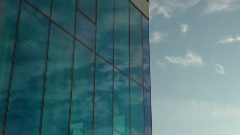 Cloud-reflections-on-a-blue-glass-building-against-a-clear-sky
