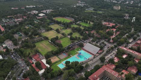 Drone-video,-sports-area-at-University-City,-featuring-training-fields-and-a-swimming-pool