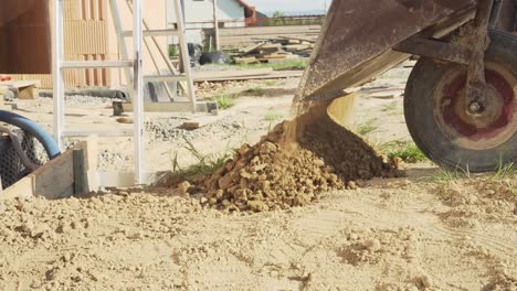 Static-shot-of-throwing-out-dirt-from-wheelbarrow-on-house-construction-site
