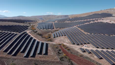 Drone-Sobre-Fila-De-Paneles-Solares-Parque-De-Energía-Solar-Fotovoltaica-Granja-Colinas-De-Montaña