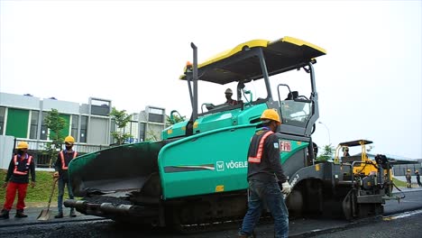 Workers-are-using-the-Asphalt-Paver-Finisher-to-spread,-level-and-compact-the-hotmix-asphalt-mixture-to-make-base,-binder-and-surface-layers-for-asphalt-road-construction