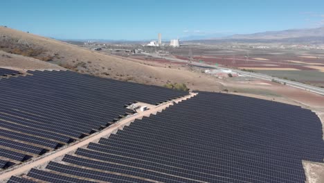 Revealing-Drone-photovoltaic-solar-power-park-farm-row-panels-coal-power-plant-background