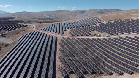 Drone-Sobre-Parque-De-Energía-Solar-Fotovoltaica-Paneles-De-Fila-Colinas-Rurales-Cielo-Azul-Soleado