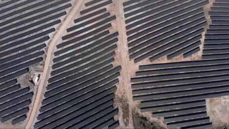 top-down-view-over-huge-photovoltaic-solar-power-park-row-panels-hills-sunny