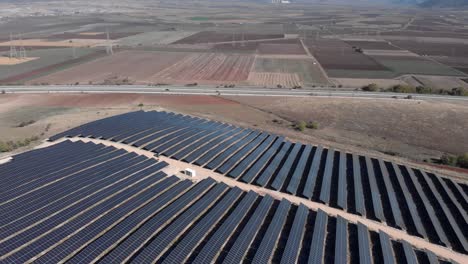 Drone-Sobre-Parque-De-Energía-Solar-Fotovoltaica-Paneles-De-Fila-Fondo-De-Calle-Principal-Rural