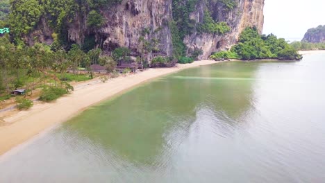 A-pull-back-aerial-drone-shot-to-slowly-reveal-the-beachfront-and-crags-in-Krabi,-in-the-south-of-Thaiiland