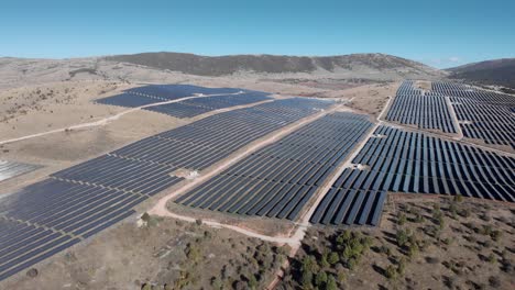 Drone-Descendente-Sobre-Un-Gran-Parque-De-Energía-Solar-Fotovoltaica-Paneles-De-Fila-De-Granja-Día-Soleado