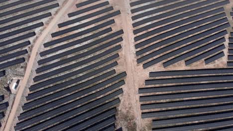 Top-Down-view-Drone-over-photovoltaic-solar-power-park-row-panels-hills-tilting