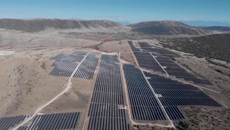 Drone-over-mega-photovoltaic-solar-power-park-farm-panels-hills-panning-right