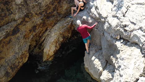 Male-and-female-climbing-on-rock-formation-to-prepare-to-cliff-dive