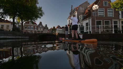 Un-Hombre-Y-Una-Mujer-Disfrutando-Del-Paddle-Surf-En-Los-Canales-Del-Centro-De-La-Ciudad-De-Haarlem.