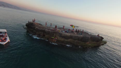 FPV-Drohne-Fliegt-In-Der-Nähe-Der-Insel-Mit-Menschen,-Die-Vor-Batroun,-Libanon,-Spaß-Haben