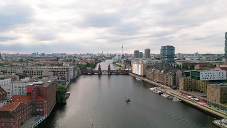 Experience-Berlin's-allure-from-the-skies-as-a-drone-gracefully-glides-over-the-Spree-River,-framing-the-iconic-Oberbaum-Bridge-and-the-captivating-city-skyline
