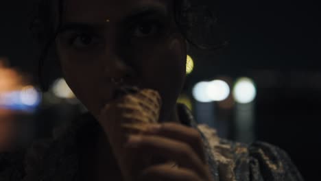 Staring-at-the-camera-of-an-Indian-girl-licking-an-ice-cream-cone-at-night-in-the-city