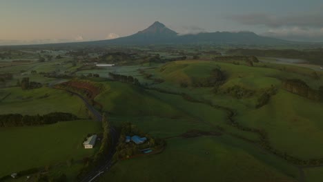 Beautiful-Mount-Taranaki-volcano-with-green-grassland-in-basin,-aerial