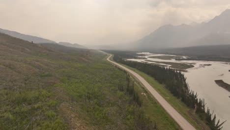 Wildfire-smoke-obscures-the-Rocky-Mountains-as-the-drone-flies-along-Highway-93-and-the-North-Saskatchewan-River-in-Alberta,-Canada