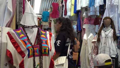 Zeitlupenaufnahme-Von-Menschen,-Die-Auf-Einem-Mexikanischen-Straßenmarkt-In-Der-Zum-Verkauf-Stehenden-Kleidung-Stöbern