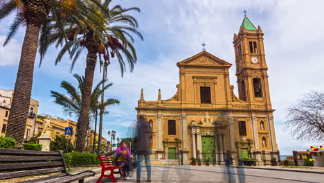 Timelapse-shot-tourists-walking-around-Termini-Imerese-Cathedral-in-Sicily,-Italy,-with-green-doors-and-windows-on-a-cloudy-day