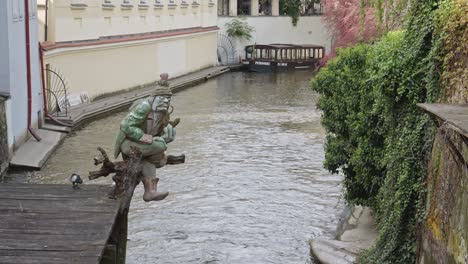 Estatua-De-Troll-Con-Una-Tubería-En-El-Canal-En-El-Centro-De-La-Ciudad-Vieja-De-Praga,-República-Checa