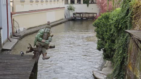 A-View-Of-Troll-Statue-With-A-Pipe-In-Canal-Near-The-Vltava-River-In-Prague,-Czech-Republic
