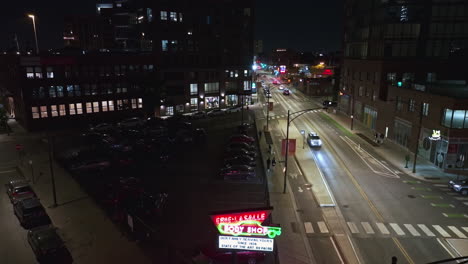 Illuminated-Erie-Lasalle-Body-Shop-sign,-in-nighttime-Chicago---Descending,-drone-shot