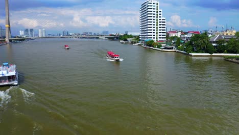 Double-decker-Tourist-Boat-And-Long-Boats-Cruising-On-The-Chao-Phraya-River-Near-Rama-VIII-Bridge-In-Bangkok,-Thailand