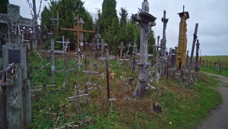 POV-shot-while-walking-along-a-path-through-the-Hill-of-Crosses-or-KRYZIU-KALNAS-in-Lithuania,-famous-religious-site-of-catholic-pilgrimage,-during-evening-time