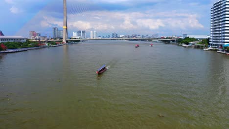 Traditionelles-Long-Thai-Boot,-Das-Auf-Dem-Fluss-Chao-Phraya-Mit-Der-Rama-VIII-Brücke-Im-Hintergrund-In-Bangkok,-Thailand,-Segelt