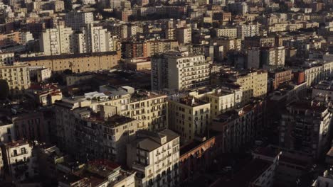 Aerial-view-showing-crowded-apartment-block-houses-in-Naples-City-build-on-hill-during-sunset-time---tilt-up-movement