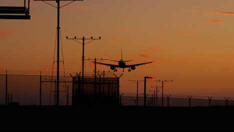 Flugzeug-Im-Endanflug-Und-Landung-Vor-Einem-Orangefarbenen-Sonnenuntergangshimmel-Am-Flughafen-Lax---Los-Angeles