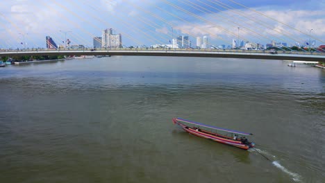 Longtail-Boat-In-The-Chao-Phraya-River-Under-The-Rama-VIII-Bridge-In-Bangkok,-Thailand